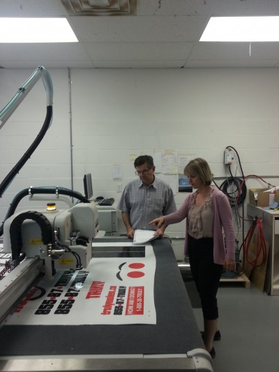 Pictured left to right are: Eddie Scraparlis, cutting table operator; and Diane Henderson, FastSigns franchisee.