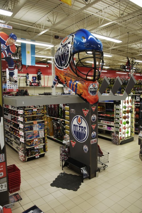 The final product is installed in a Canadian Tire store, hanging above a related merchandising display.