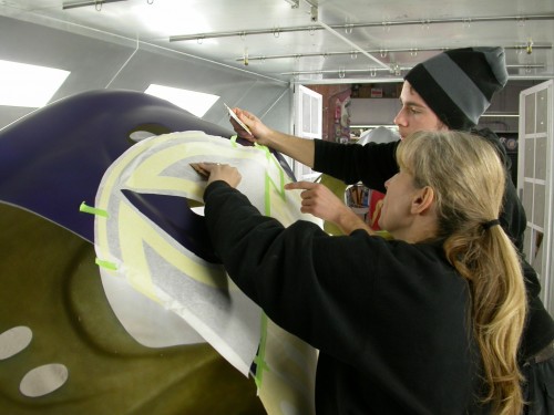 Paint masks are applied to the surface, laying out the logos and lettering. A lot of tweaking is needed to ‘pinch’ two-dimensional (2-D) graphics to the three-dimensional (3-D) object.