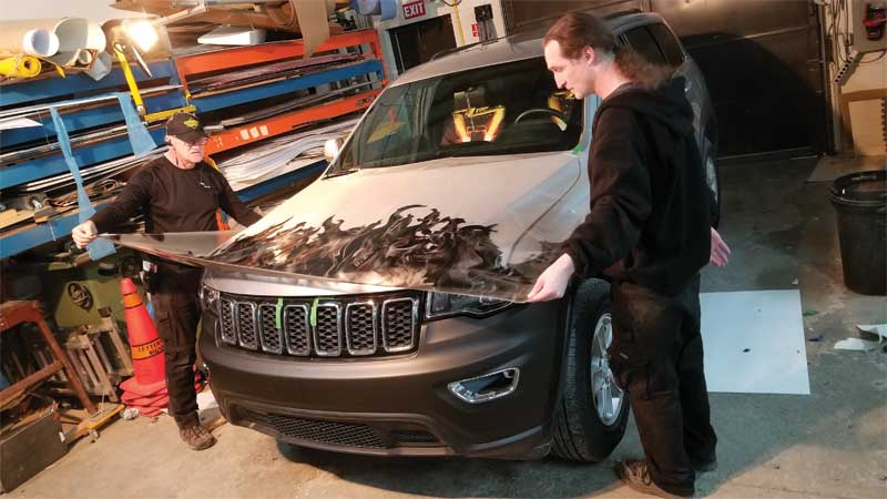 The badging and washer nozzles were removed to install the wrap. The film was carefully positioned in place.