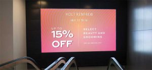 A digital mall billboard advertising the Holts campaign.