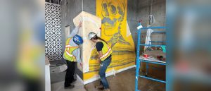 Applying the contour-cut stencil to the wall at TX/MX.