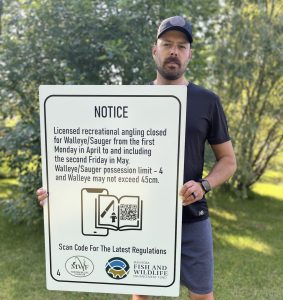 Chase Dreilich, recreational angling coordinator at MWF, holding the sign.