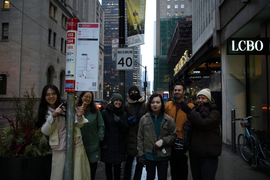 TTCriders pose for a photo near bus stop signage. 
