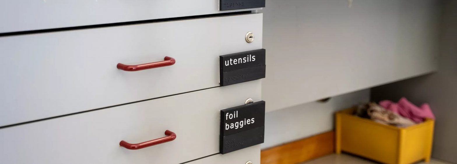 The Braille signs on drawers to help identify what is in them, such as utensils.