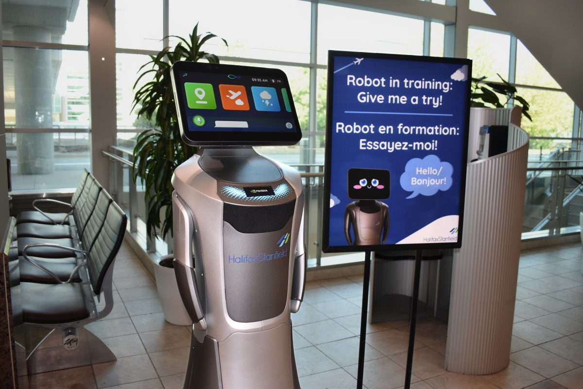 The robot at the airport is alongside a bilingual sign encouraging people to use it.