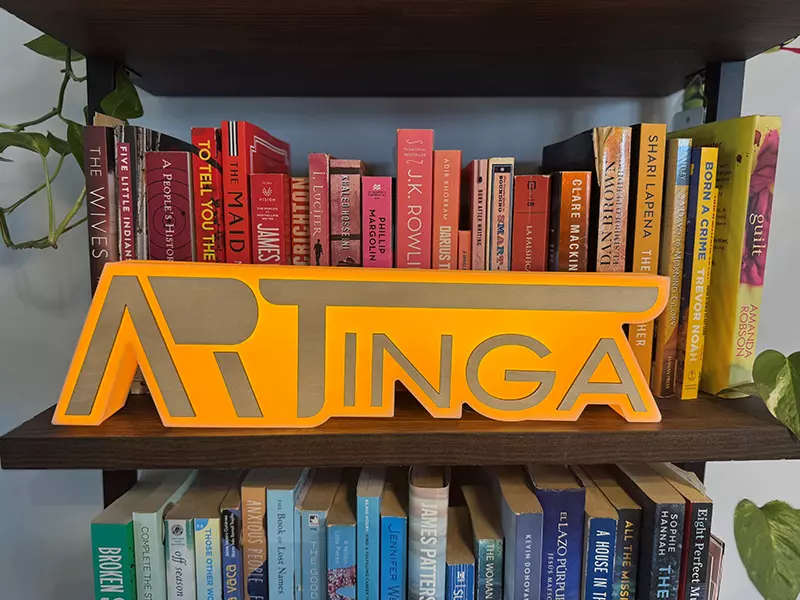A 3D printed sign placed on a bookshelf.