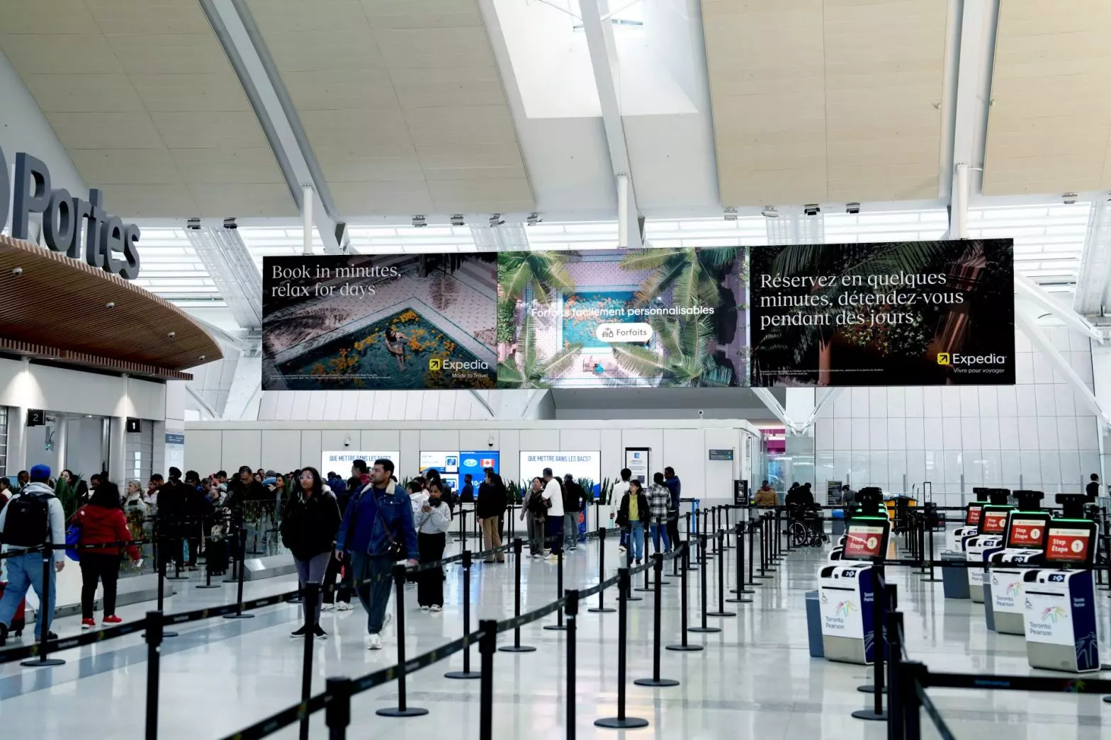 Pattison ads are displayed at the airport as people queue up.