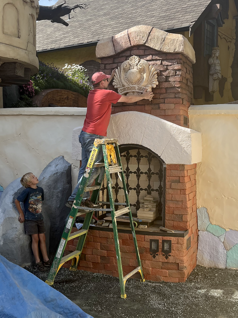 Peter and his son, Henry, hang the Copper Crown crest over the outdoor fireplace.