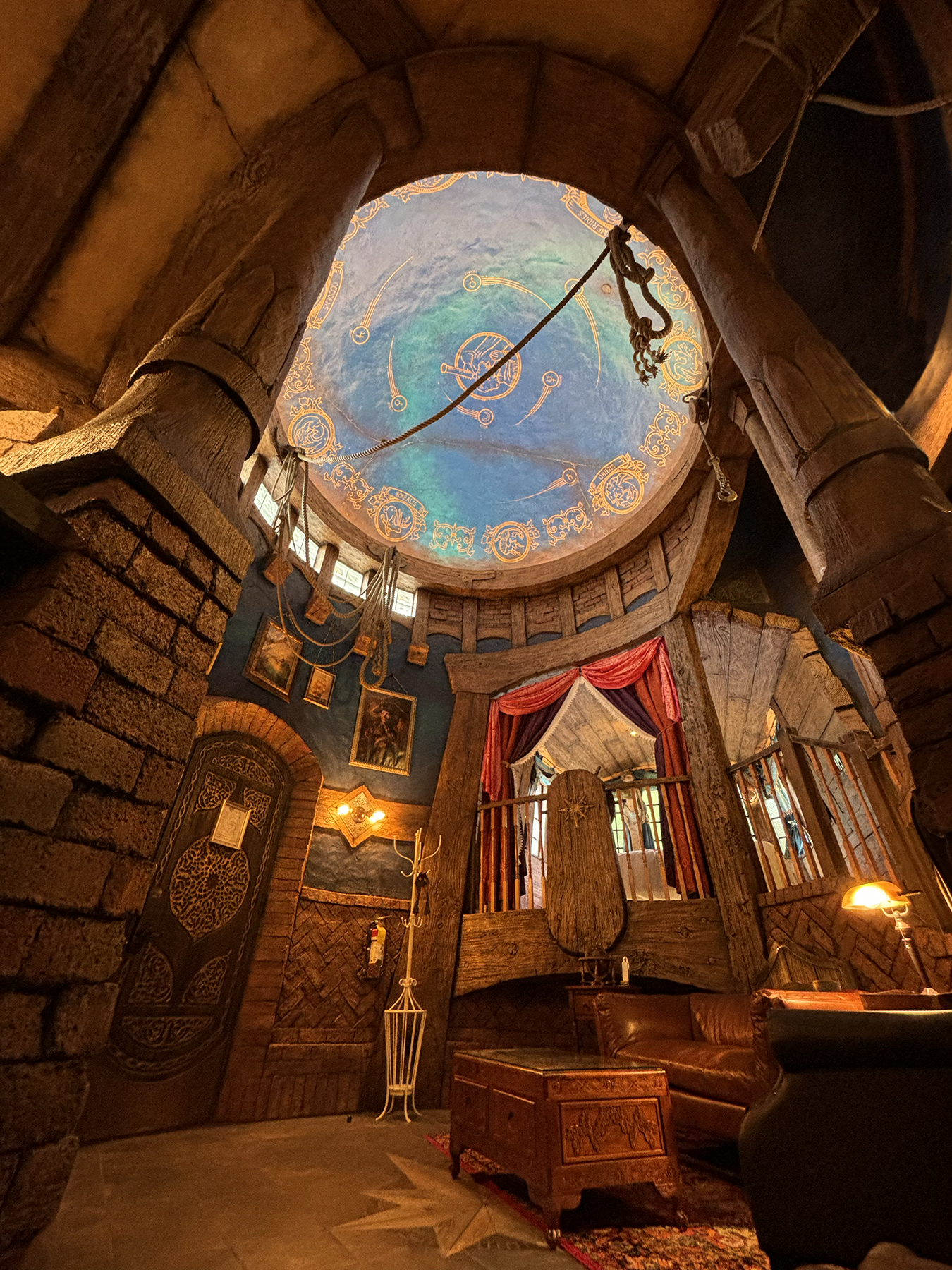 Interior of a fantasy-themed tower room with a painted celestial dome ceiling and stone arched walls