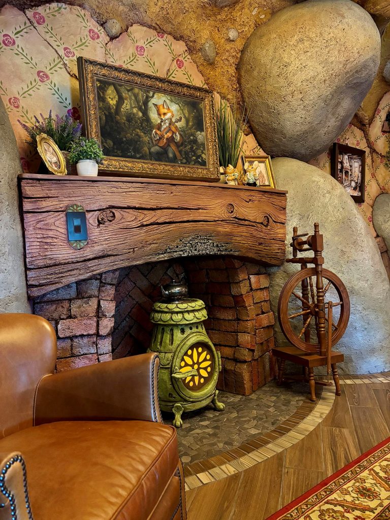 Fireplace: While modern in function, the features appear to be antiquated. The potbellied stove glows with a “fire” inside. However, guests who study the fireplace mantle will notice the slightly charred timber, which is carved from concrete and painted exquisitely. The photo on the mantle is a hidden television for guests.