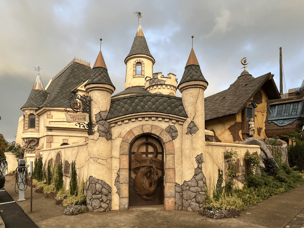 Exterior of Copper Crown, a fantasy-themed castle building with multiple turrets, a dragon door, and crumbling stone facade