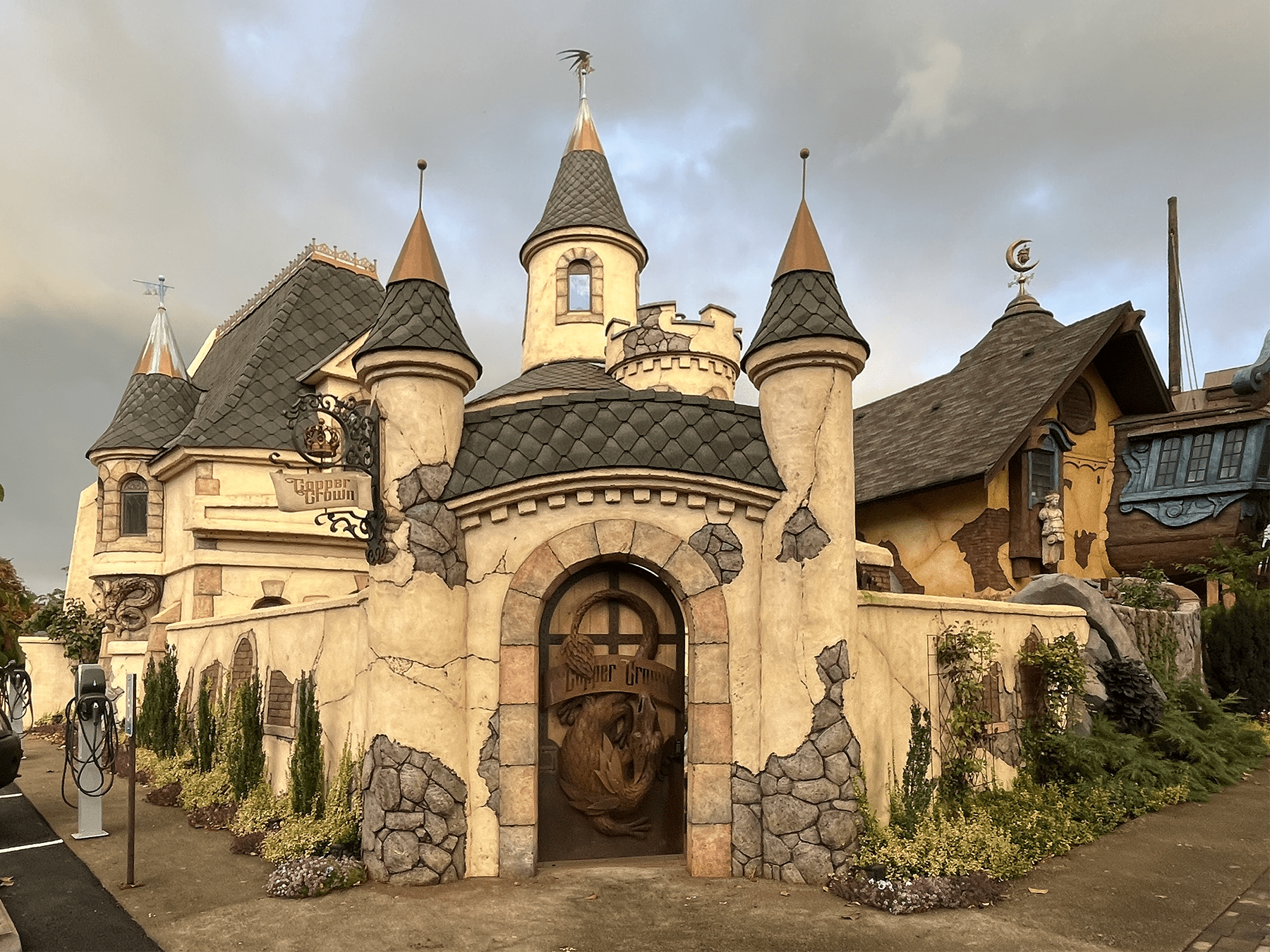 Exterior of Copper Crown, a fantasy-themed castle building with multiple turrets, a dragon door, and crumbling stone facade
