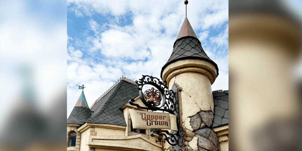 Exterior of Copper Crown, a fantasy-themed castle building with multiple turrets, a dragon door, and crumbling stone facade