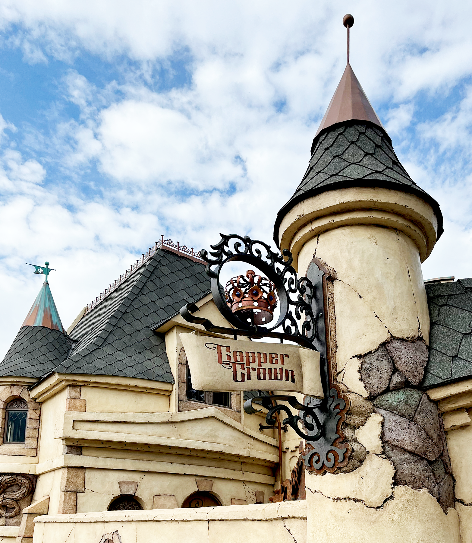 Exterior of Copper Crown, a fantasy-themed castle building with multiple turrets, a dragon door, and crumbling stone facade