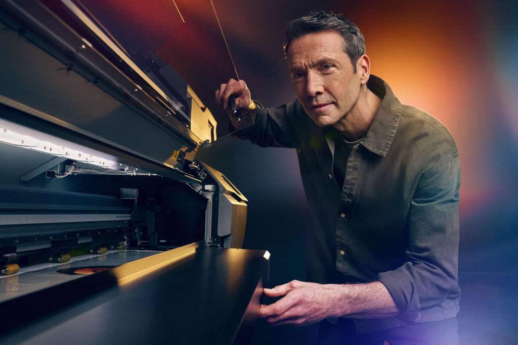 A person stands alongside a Roland DG printer. 