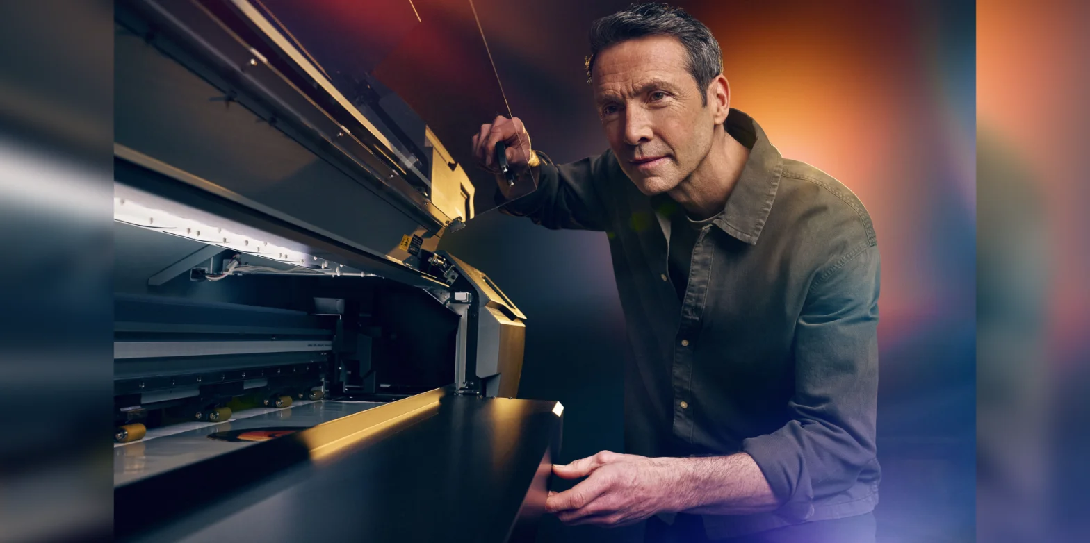 A person stands alongside a Roland DG printer.