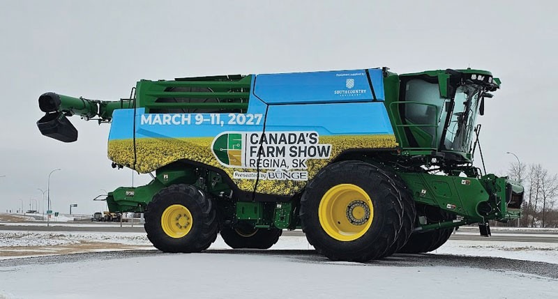 A green John Deere combine harvester is wrapped with promotional signage for Canada's Farm Show in Regina, SK, March 9–11, 2027, presented by Bunge, parked outdoors.