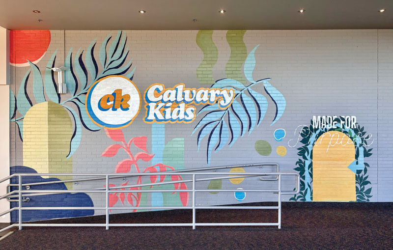 A colourful mural with palm leaves and geometric shapes reads "Calvary Kids" and "Made for Purpose" on a hallway wall.