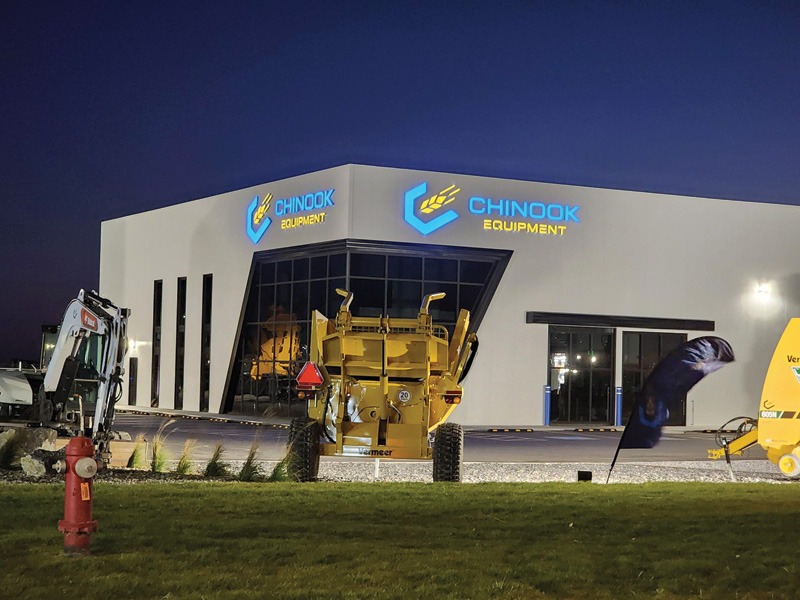 Chinook Equipment building at night with illuminated blue channel-letter logo and wordmark on two sides of the facade.