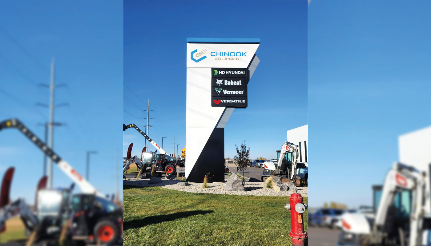 Tall black and white pylon sign for Chinook Equipment with an illuminated multi-tenant panel listing HD Hyundai, Bobcat, Vermeer, and Versatile.